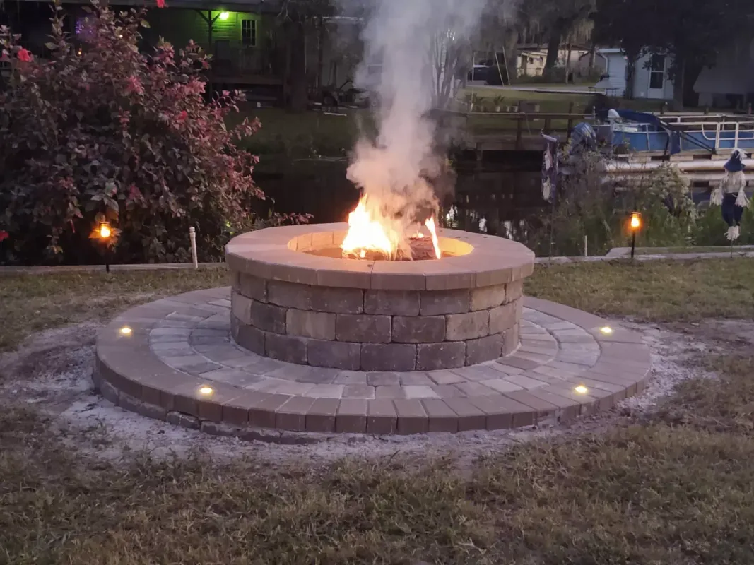A fire pit is sitting in the middle of a lush green field.